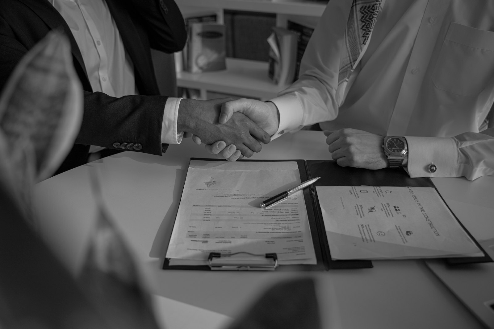 two people shaking hands over a piece of paper