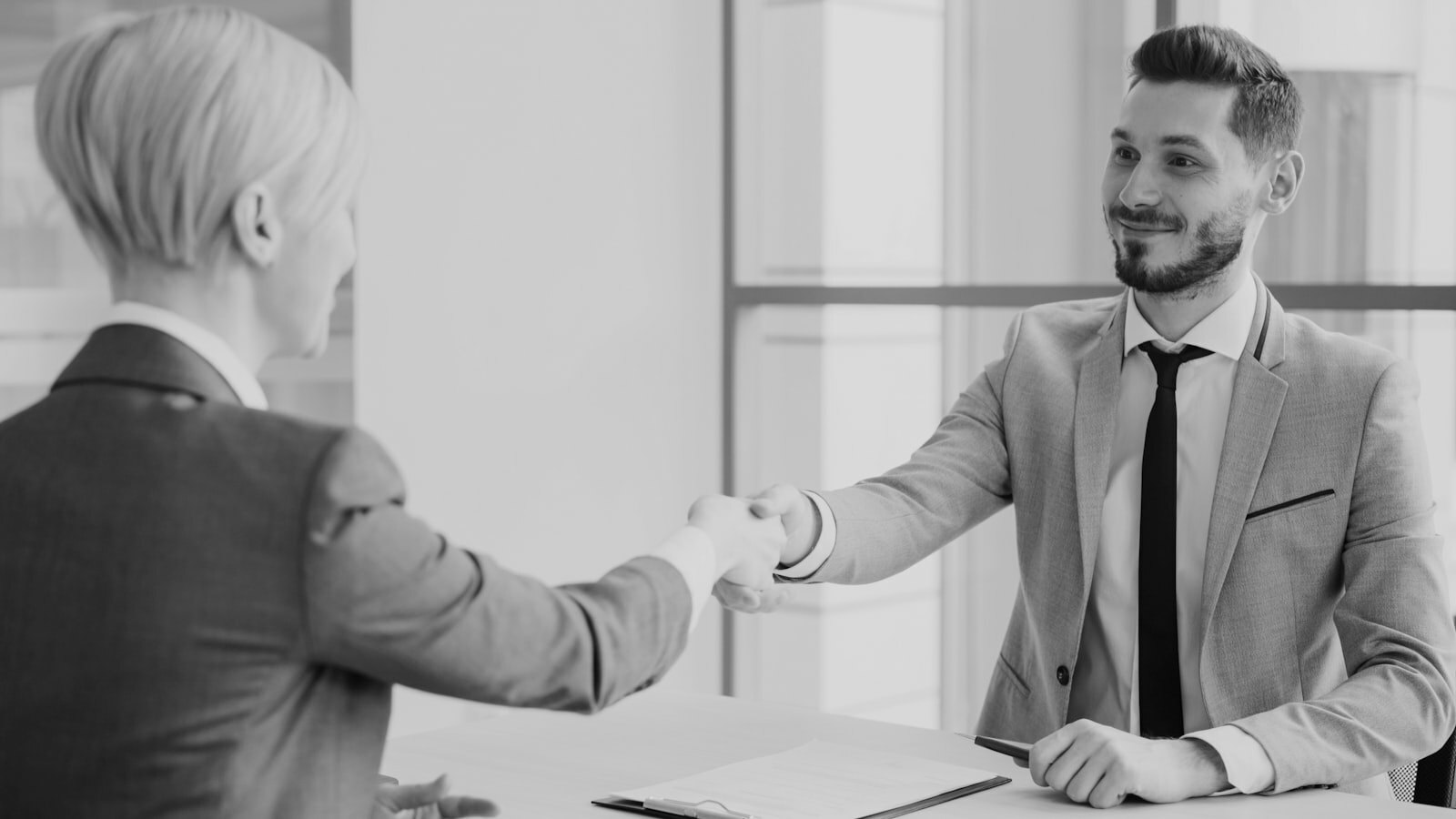 Two professionals shaking hands across a table
